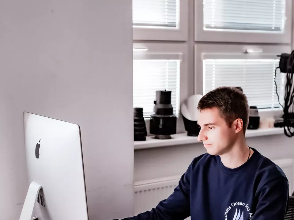 Vývojár Business Ocean skladá rozloženie stránky na iMacu pri stole v štúdiu